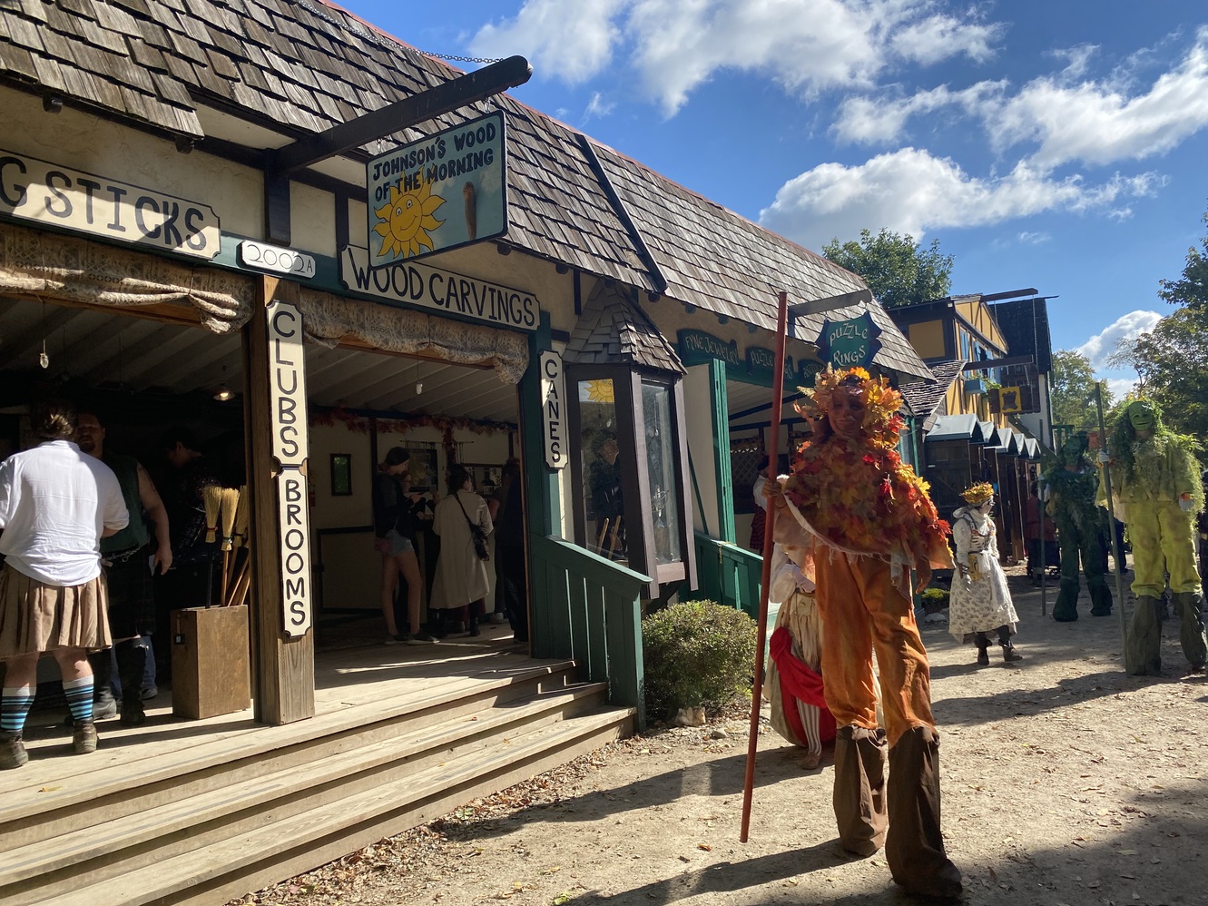 An "ent" performer strolls by an artisanal
        shoppe.