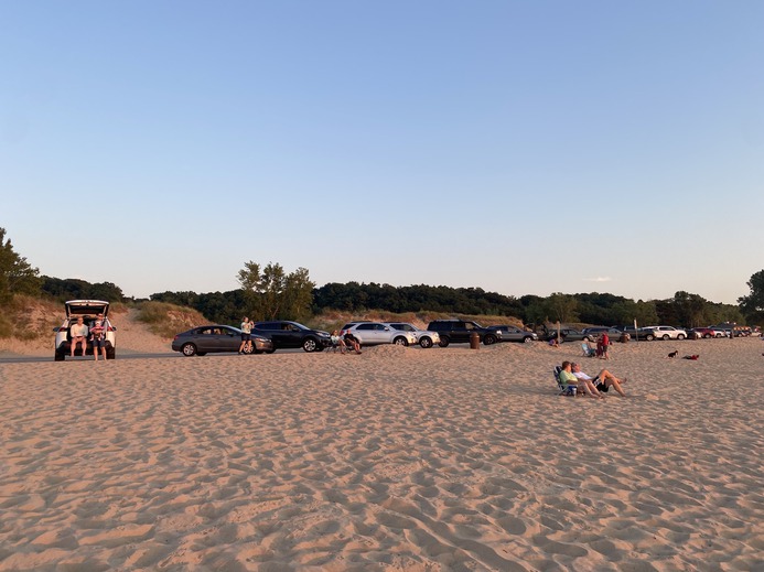 People sit in or near their cars for the sunset on August 23
      2022.